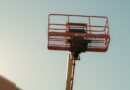 Orange boom lift basket against a clear sky