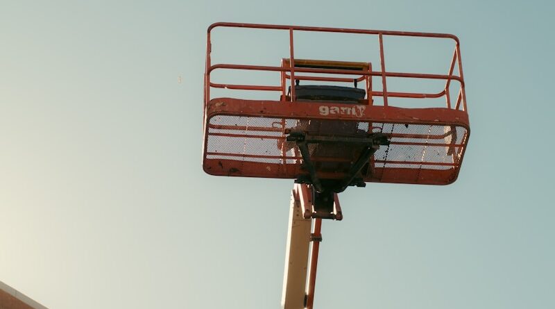 Orange boom lift basket against a clear sky